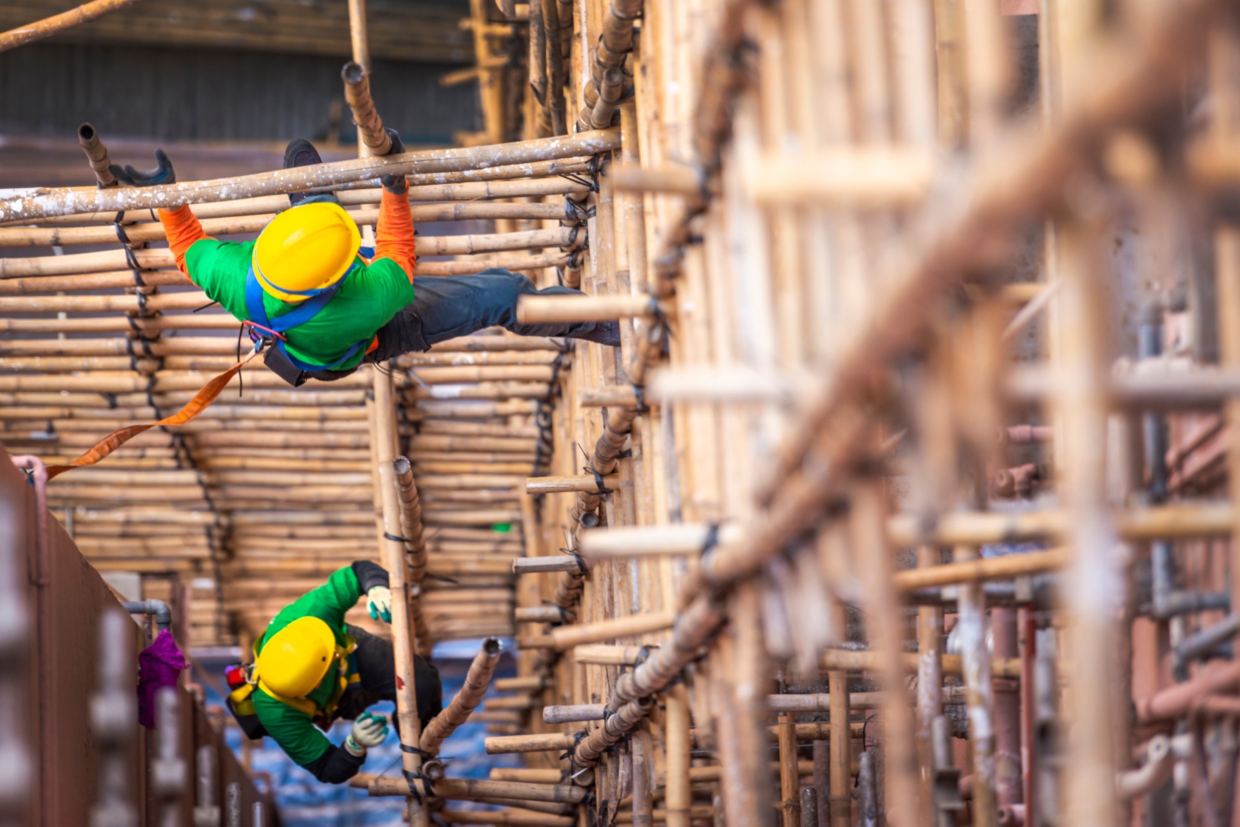 Workers using bamboo scaffolding to access a building exterior